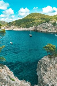 pexels-photo-2191136-2191136 Sailboats drift in a stunning turquoise bay surrounded by rocky cliffs in Ibiza, Spain.